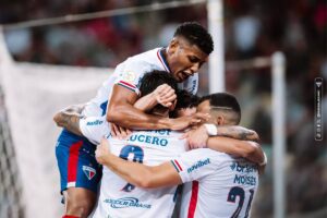 Jogadores do Fortaleza comemoram gol se abraçando.