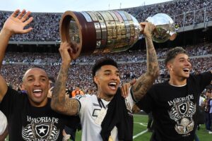 Imagem do atacante Igor Jesus, do Botafogo, segurando a taça da Libertadores entre companheiros. Foto: Vítor Silva/Botafogo